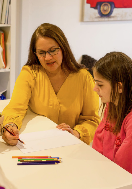 Sim guiding a school-age child through a writing exercise