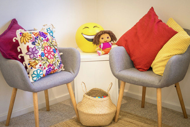 Cosy therapy corner with armchairs, colourful cushions and a basket of toys